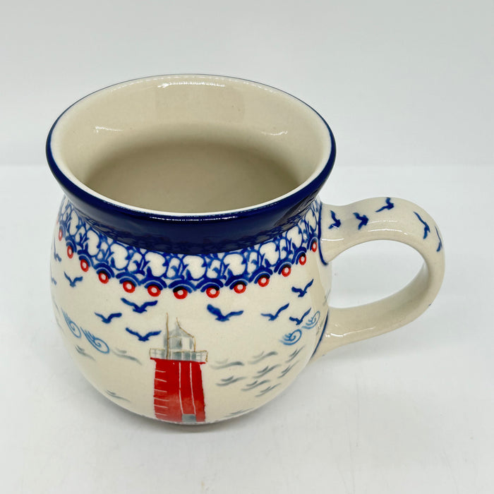 Angled top-down view of a large 16oz Ceramika Artystyczna Polish pottery bubble mug in the Unikat U5164 pattern, showing the lighthouse exterior, and a clean, undecorated interior.