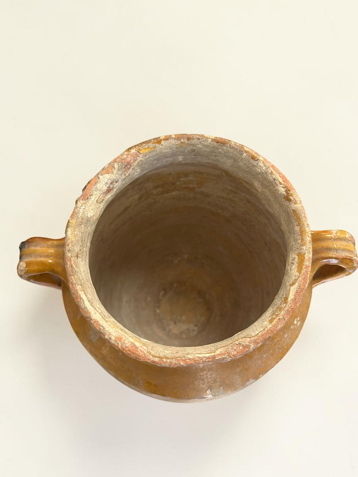This is a 19th-century French terracotta confit pot with a partially yellow-glazed finish